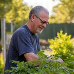 Candid photo of Jason Kelly, a retired Boulder resident, tending to his thriving vegetable garden, looking content with a slight smile.