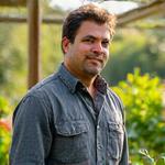 Portrait of Michael Rodriguez, a horticulturalist, standing in a lush, healthy garden.